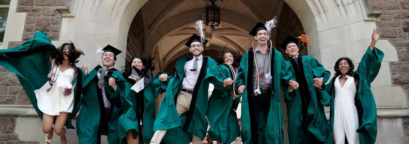 Photo of a group of WashU graduates gleefully jumping into the air together