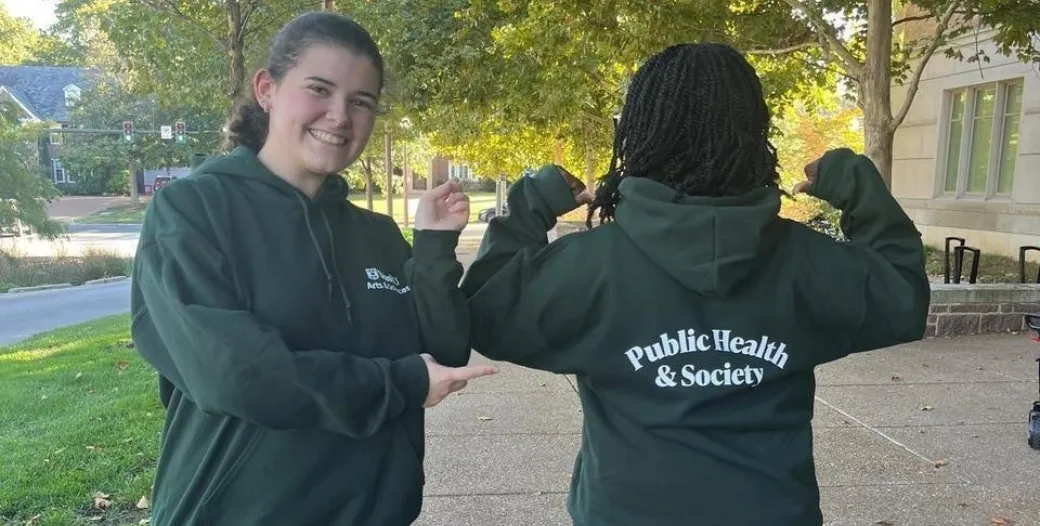Two students posing with Public Health & Society sweatshirts