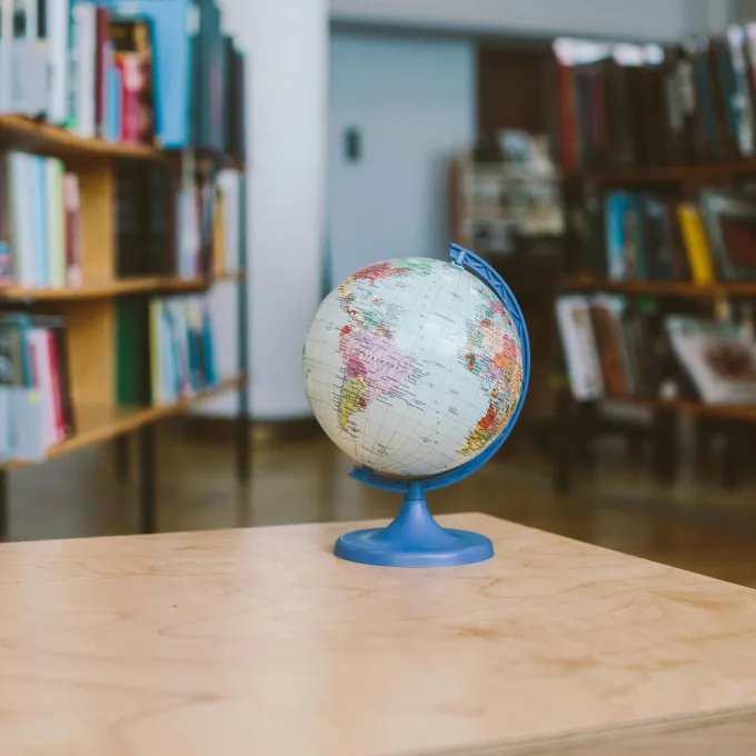 a photo graph of a small globe with a library in the background